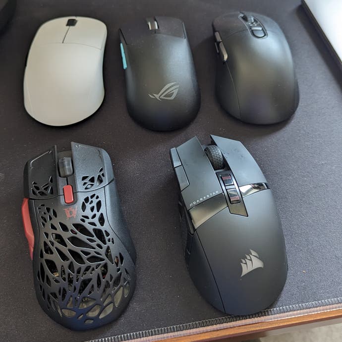 a collection of five gaming mice sitting on a desk